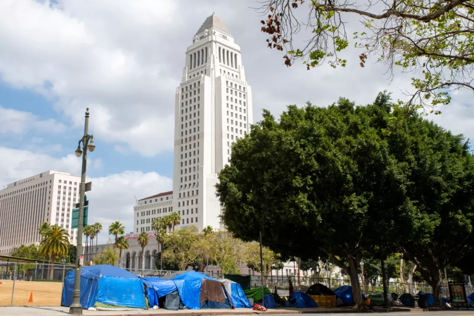 A group of tents line a street in front of Los Angeles City Hall.